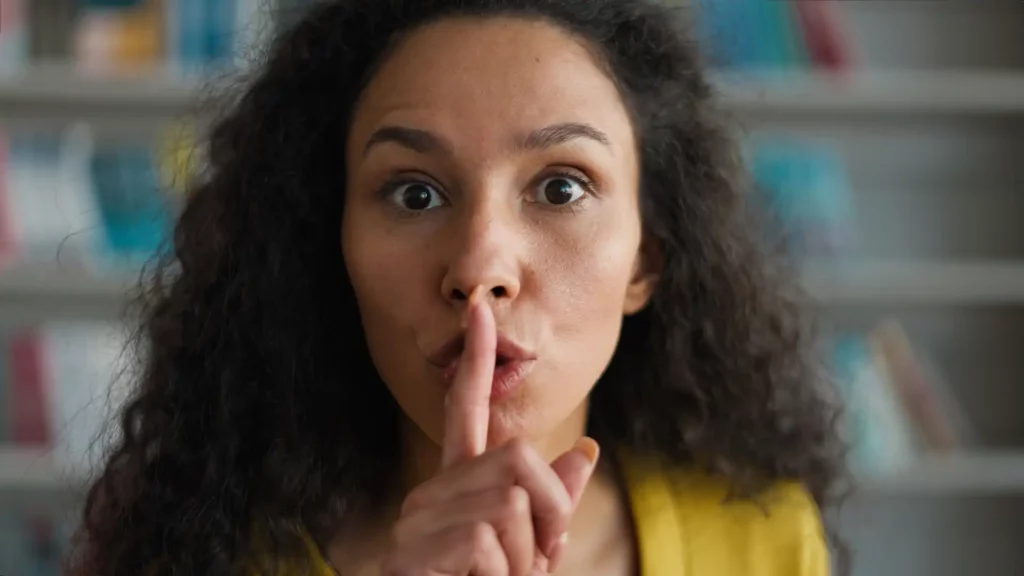 Mulher fazendo sinal de silêncio, destacando a importância de respeitar as regras dos condomínios para manter a harmonia no ambiente compartilhado.