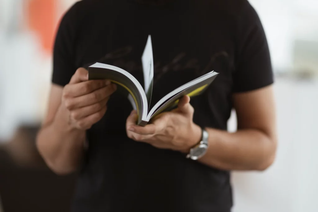 Pessoa segurando manual do proprietário aberto, importante para consultas sobre manutenção e uso de veículos
