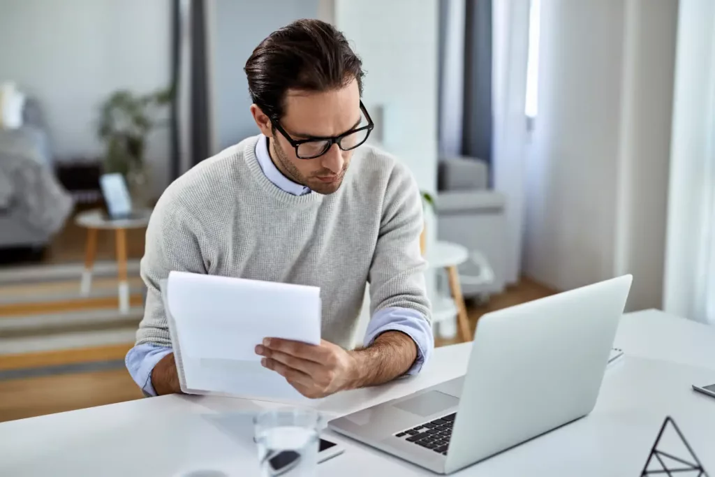 Homem analisando documentos relacionados à alienação fiduciária de imóvel em ambiente de escritório modernocomeço